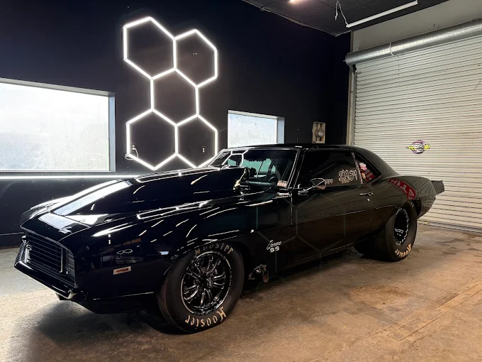 Glossy black 1969 Camaro SS under the hexagon shop lights