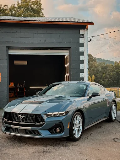 Blue Ford Mustang outside the open bay door